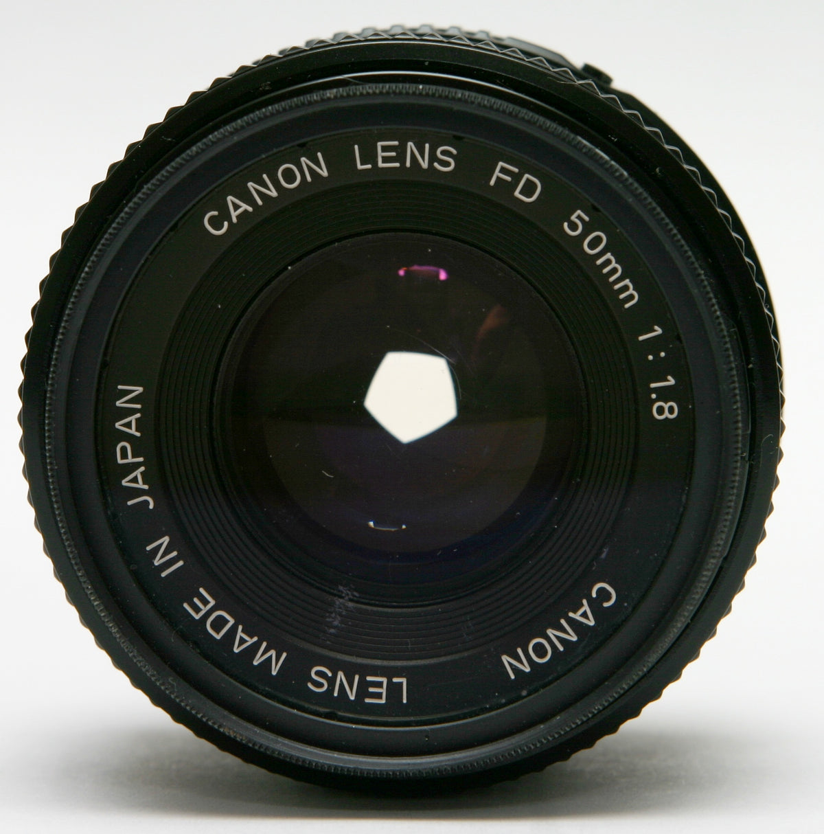 Canon New FD 50mm f/1.8 lens seen from the front, black barrel, "Canon Lens FD 50mm 1:1.8" engraved on the name ring, five-bladed aperture stopped down