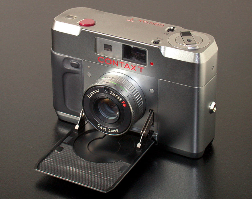 Contax T compact rangefinder in silver, front view with the lens cover folded down